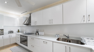 Kitchen with oven, microwave and toaster along white gloss cabinetry at Smugglers Cove 3 on the west coast of Barbados