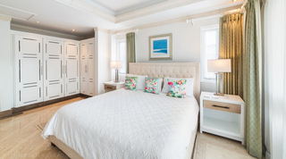 Flamingo-cushioned king bed and white fitted wardrobes in a bright bedroom at Smugglers Cove 3 in St. James, Barbados