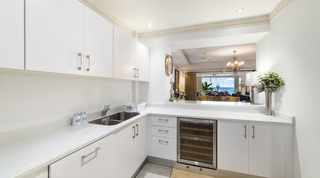 White kitchen with a wine fridge and serving hatch through to the living room and sea, Smugglers Cove 3, Barbados