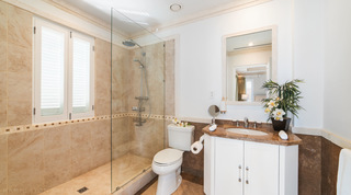 Walk-in shower behind a frameless glass screen with a mosaic tile border in a Smugglers Cove 3 bathroom, Barbados