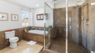 Bathroom with turtle and seahorse prints, a tiled built-in bath and glass shower at Smugglers Cove 3, Barbados