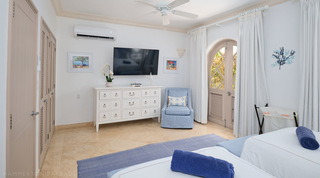 St. Peter's Bay 104 twin room with a chest of drawers, blue armchair and colourful Caribbean prints, Barbados