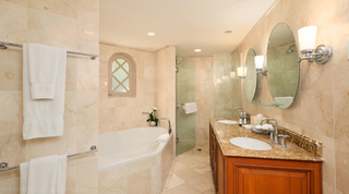 Bath beneath an arched window with a glass shower and double vanity beyond, St. Peter's Bay 104 in Barbados