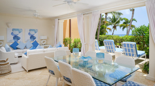 Glass-topped terrace dining table beside sun loungers facing the sea at St. Peter's Bay 104, apartment rental in Barbados