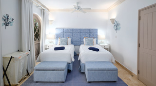 Twin bedroom with a blue coral-print headboard and matching storage benches at St. Peter's Bay 104, west coast Barbados