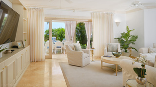 TV on built-in cabinetry and doors open to terrace dining, St. Peter's Bay 104 holiday apartment in Barbados