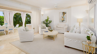 Living room with a white slipcovered sofa, armchairs and gold abstract artwork at St. Peter's Bay 104 in Barbados