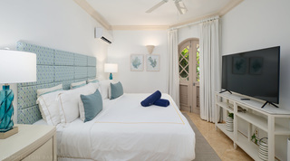 Double bedroom with an aqua patterned headboard and arched garden doors at St. Peter's Bay 104, Barbados