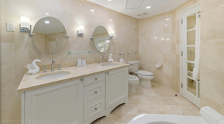 Twin basins, round tilting mirrors and glass shelves beside a bidet and WC, a bathroom of St. Peter's Bay 106, Barbados