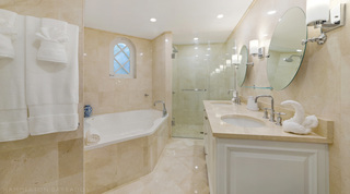 Bathroom with a built-in bath beneath a small arched window and a twin-basin vanity at St. Peter's Bay 106 in Barbados