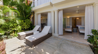 Wicker sun loungers on the garden patio beside twin columns at St. Peter's Bay 106 in St. Peter, Barbados
