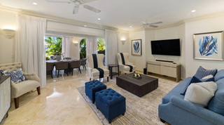 Blue sofa, navy-striped wingback chairs and deep blue tufted ottomans in the St. Peter's Bay 106 living room, Barbados