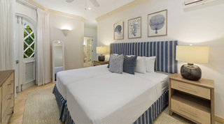 Twin beds with a blue-and-white striped headboard and valance at St. Peter's Bay 106, holiday apartment in Barbados