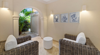 St. Peter's Bay 106 sitting nook with wicker armchairs and coral prints, its arch opening onto a gravel garden, Barbados