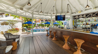 Resort bar with sculpted wooden stools and a stocked back bar beside the communal pool, St. Peter's Bay 106, Barbados