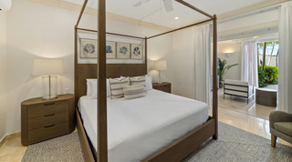 Wooden four-poster bed beneath blue seaweed prints at St. Peter's Bay 106, luxury apartment in Barbados
