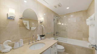 Glass-screened shower over the bath and an orchid by the basin at St. Peter's Bay 106, apartment rental in Barbados