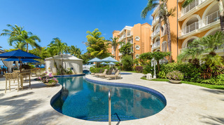Winding communal pool with a white footbridge and sun loungers at the resort that is home to St. Peter's Bay 106, Barbados