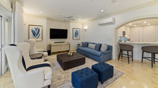 Wingback armchairs and a blue sofa beside an arch to the breakfast bar, St. Peter's Bay 106, Barbados apartment rental