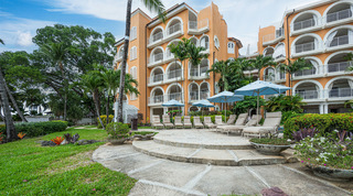 Round stone sun terrace with loungers and pale blue parasols in the gardens of St. Peter's Bay 204, on Barbados' west coast