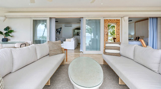 Open sliding doors from the covered terrace into the white living room at St. Peter's Bay 204, a Barbados apartment rental