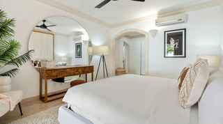 Large round mirror behind a chunky wood-block console in a St. Peter's Bay 204 bedroom, Barbados