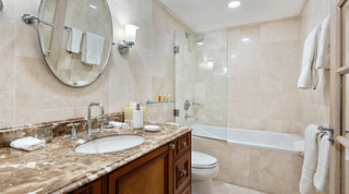 Wooden vanity with a woven door panel beside a glass-screened bath at St. Peter's Bay 204, Barbados