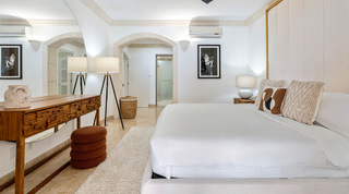 St. Peter's Bay 204 bedroom looking towards its stone-trimmed arched doorway and a woven laundry basket, Barbados