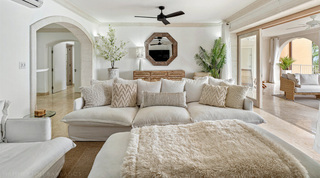 Deep white sofa and an octagonal wooden mirror above the sideboard in the living room of St. Peter's Bay 204, Barbados