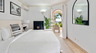 Bedroom with black and white cushions and a door open to a sea-view balcony at St. Peter's Bay 204 in Barbados