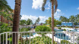 Balcony view over gardens to the lagoon-style communal pool and sea, St. Peter's Bay 207 beach apartment, Barbados