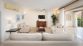 Living room with cream sofas, a wall-mounted TV and sliding doors open to the terrace at St. Peter's Bay 207, Barbados
