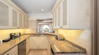 Kitchen with lattice-front cabinets, granite worktops and a pass-through to the terrace, St. Peter's Bay 207, Barbados