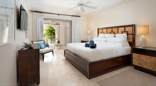 King bedroom with a burr wood headboard opening to an arched balcony, St. Peter's Bay 207, west coast Barbados apartment