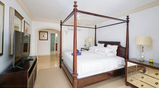 Four-poster bed, mirrored bedside chest and arched passage to the bathroom, St. Peter's Bay 308, luxury apartment in Barbados