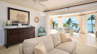 Sepia tall-ship print over a dark wood sideboard, sea views through the terrace arches, St. Peter's Bay 308, Barbados