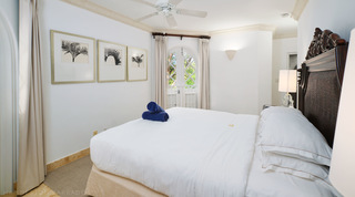 Three framed black-and-white palm prints by a white bed, arched lattice doors at the far end, St. Peter's Bay 308, Barbados