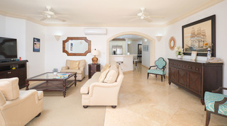 St. Peter's Bay 308's living room arch opens to the breakfast bar, a cut-corner mirror beside it, apartments in Barbados