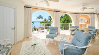 On St. Peter's Bay 308's arched terrace in Barbados, blue-cushioned armchairs around a basketweave-pattern coffee table