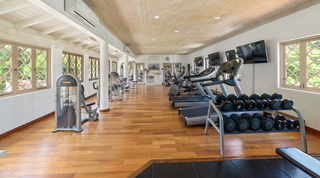 Plank-floored shared gym with two tiers of dumbbells, wall-mounted TVs and cardio machines, St. Peter's Bay 308, Barbados