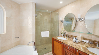 Towel on a glass shower door behind a bath with a tall chrome tap, in another bathroom at St. Peter's Bay 308 in Barbados