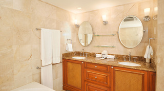 Wooden twin-basin vanity with woven door panels and oval tilting mirrors, St. Peter's Bay 401, a Barbados apartment rental