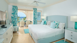 Pale blue winged headboard and turquoise leaf-print curtains in a sea-view bedroom of St. Peter's Bay 401, Barbados
