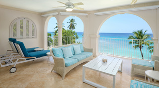 Two blue-cushioned sun loungers and a woven sofa on the covered sea-view terrace at St. Peter's Bay 401 in Barbados
