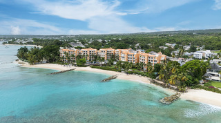 Drone view over a white-sand bay to the apricot resort that is home to St. Peter's Bay 401, luxury apartment in Barbados