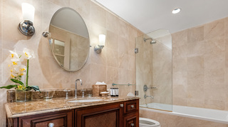 White orchid by the basin and a glass-screened shower over the bath in a St. Peter's Bay 404 bathroom in Barbados