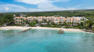 Aerial view over rock groynes and turquoise water to the apricot beachfront home of St. Peter's Bay 404, Barbados