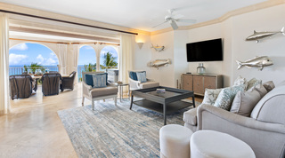 Living room with silver fish sculptures and cane-sided armchairs opening onto the terrace at St. Peter's Bay 404, Barbados