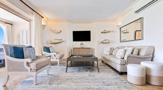 Sofa with starfish cushions, twin pouffes and silver fish sculptures at St. Peter's Bay 404, a Barbados apartment rental
