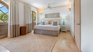 Split upholstered headboard, turquoise glass lamps and an arched lattice door in a St. Peter's Bay 404 bedroom, Barbados